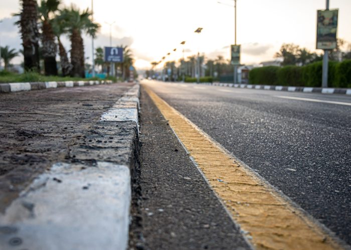 city asphalt road with palm trees along the road at sunset.